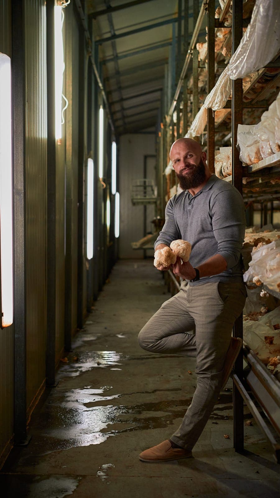 Cezary Szewczuk, COO of Mushroom Empire, in the Lion's Mane cultivation corridor with UV growth lights — facility in Lublin region, Poland.